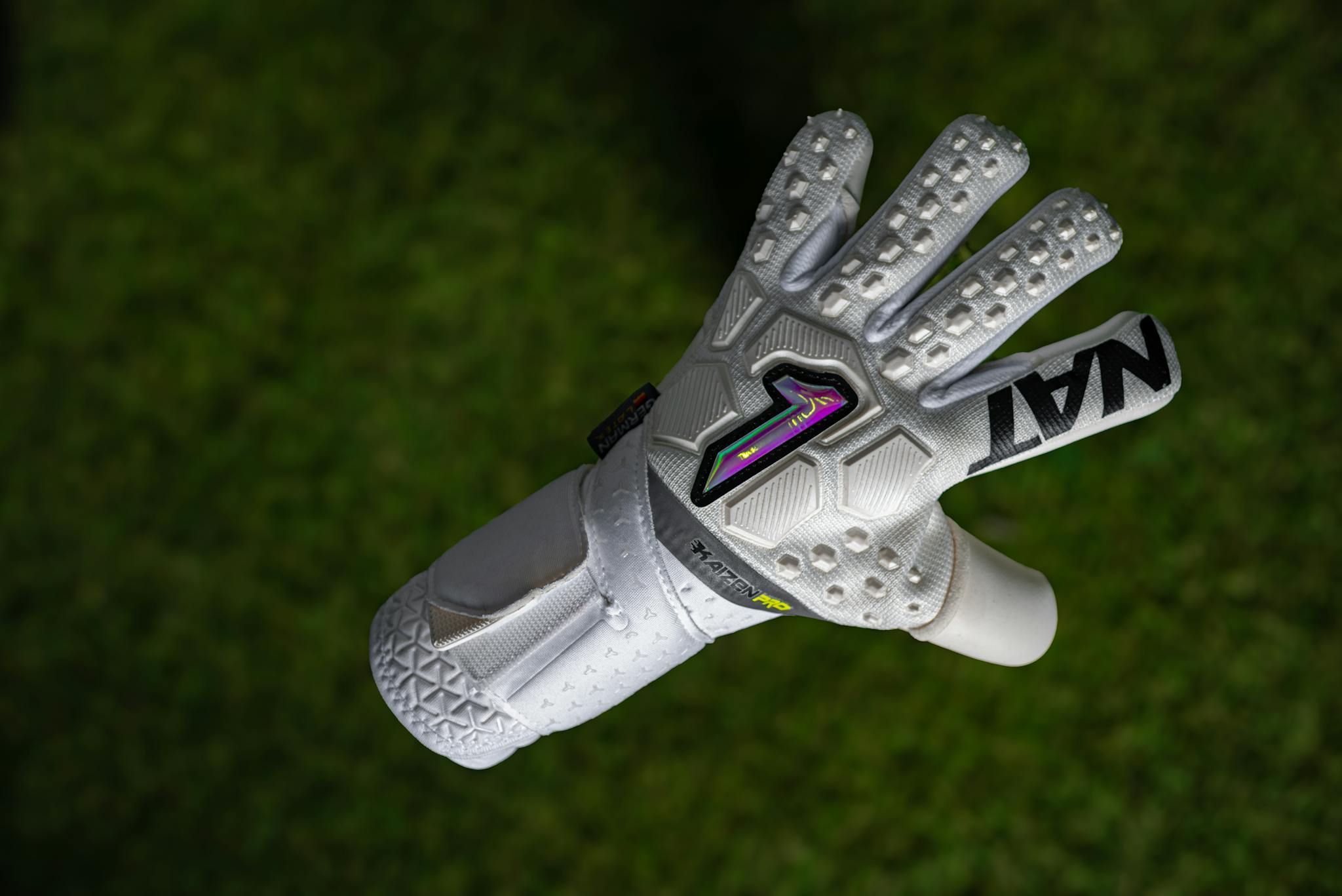 Close-up of a white goalkeeper glove on lush green grass, suitable for sports-focused visuals.