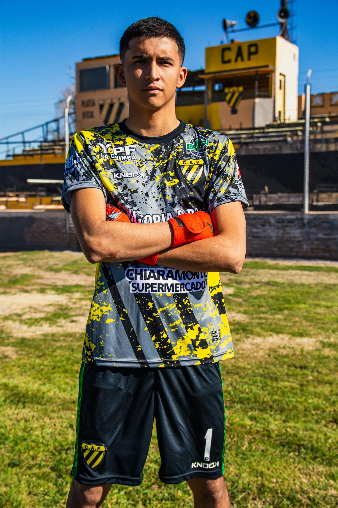 Confident young soccer player posing outdoors in a stadium.