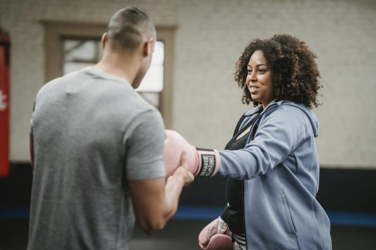 Female and male trainers practicing boxing techniques in a gym setting.
