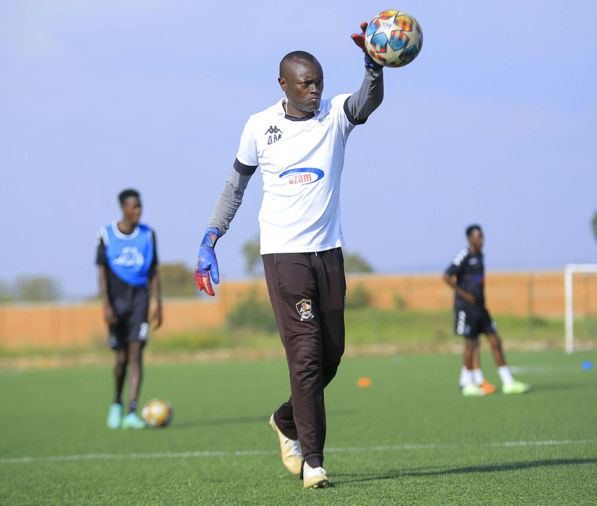Goalkeeper throwing soccer ball during outdoor team training session.