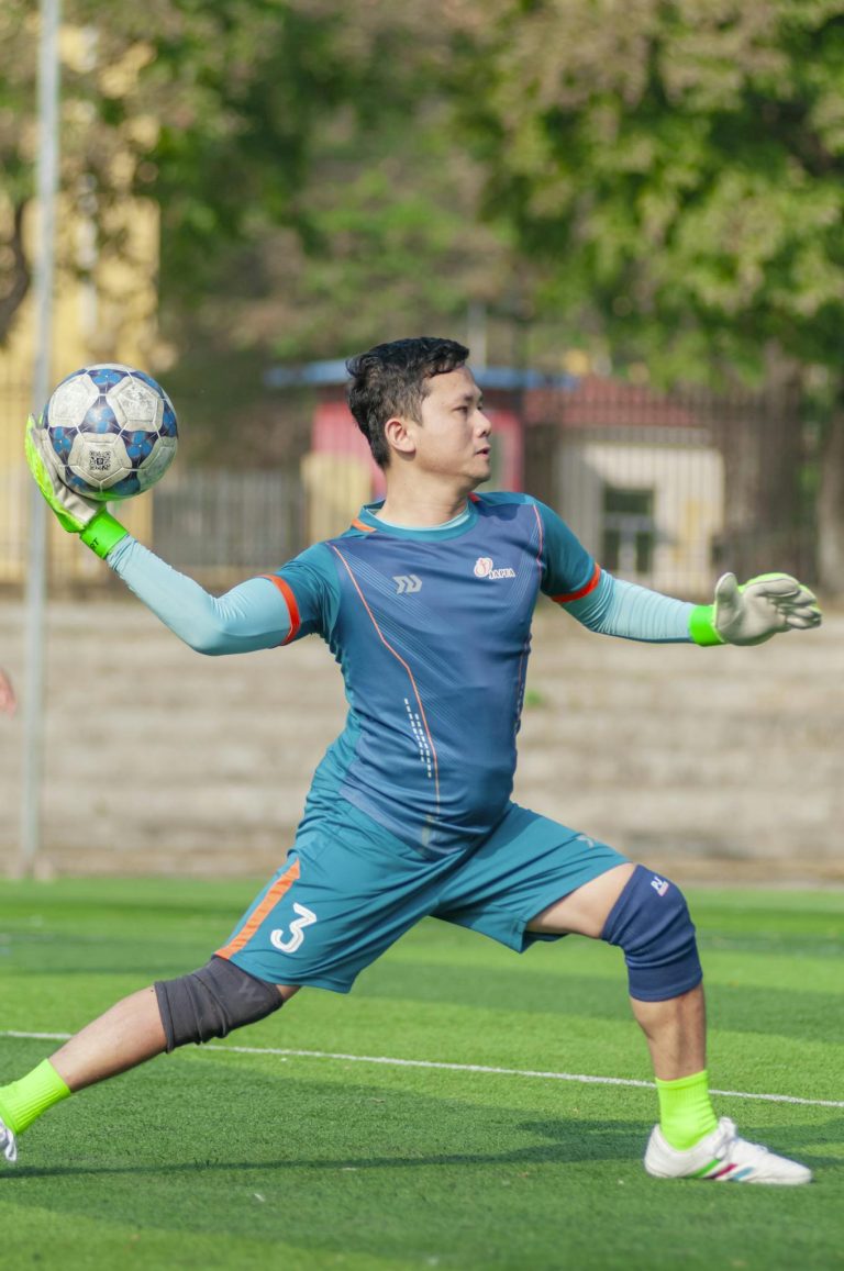 Soccer goalkeeper practicing throw on sunny day in Hanoi, Vietnam.
